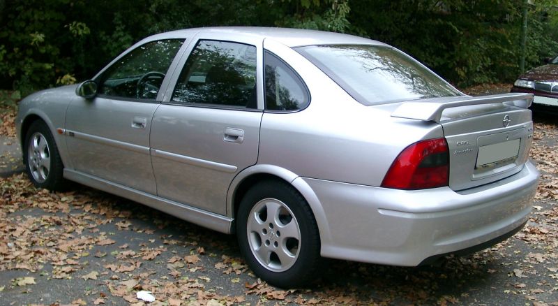 Rear-side view of a silver sedan with rear spoiler and alloy wheels