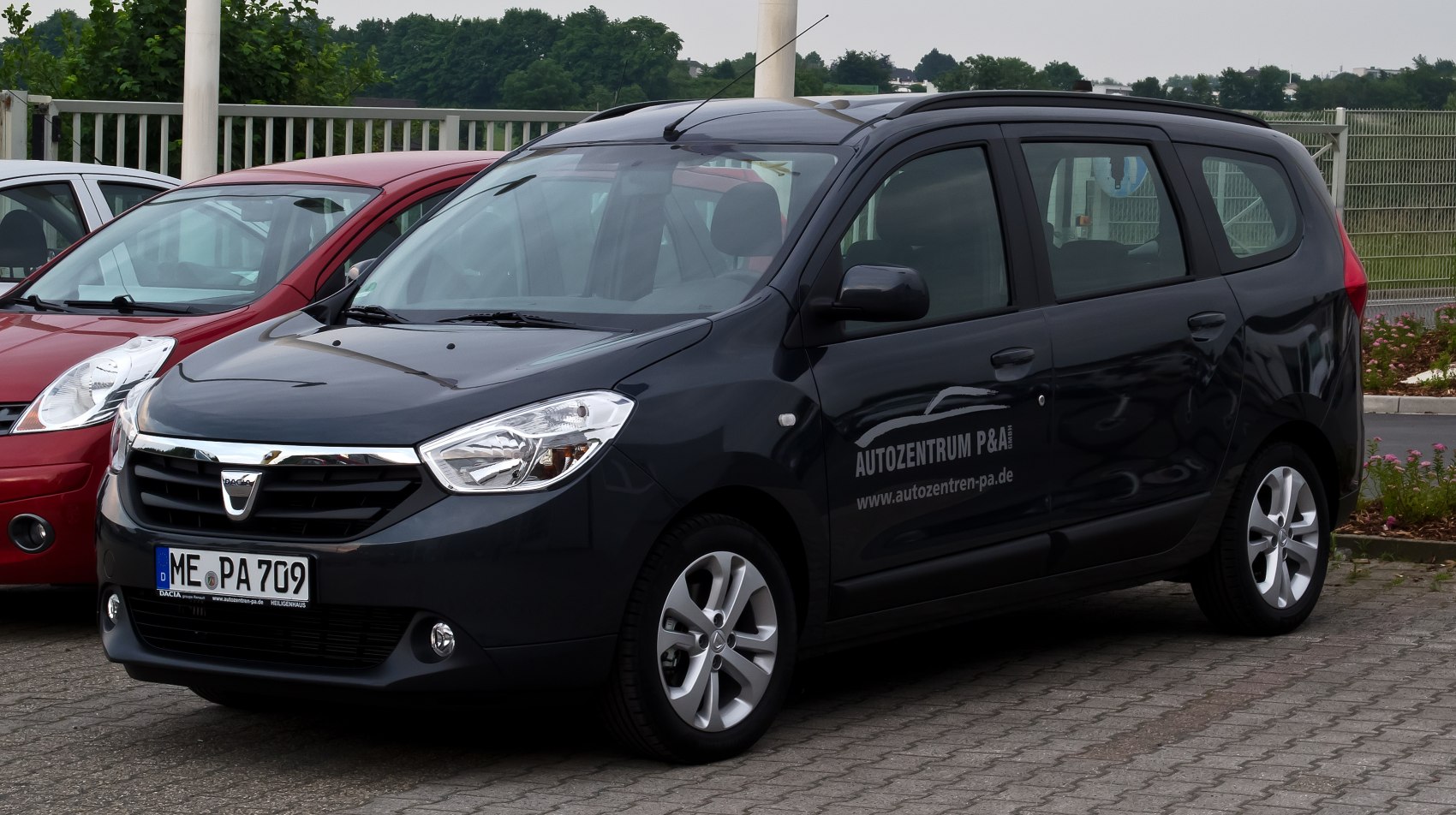 Multi-passenger vehicle front and side view with chrome grille and alloy wheels