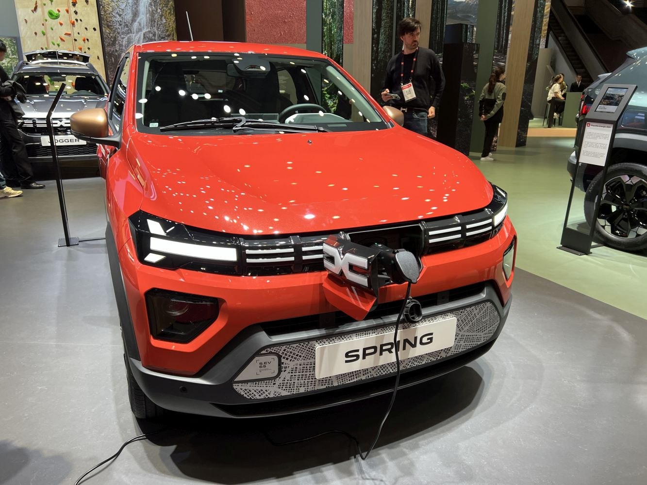 Electric vehicle front with LED headlights and visible charging port.