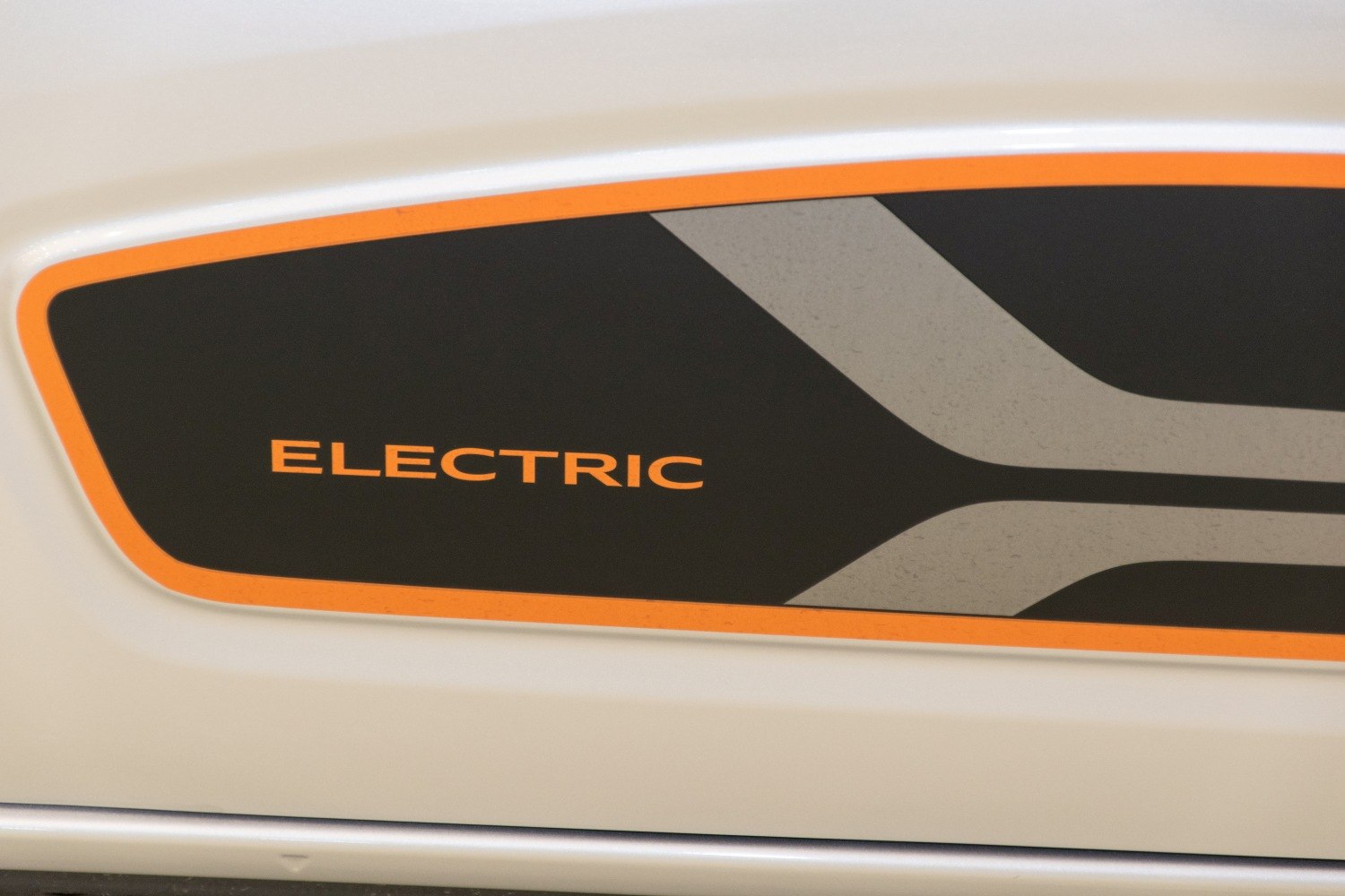 Close-up of electric badge on vehicle's body with black, orange, and grey design