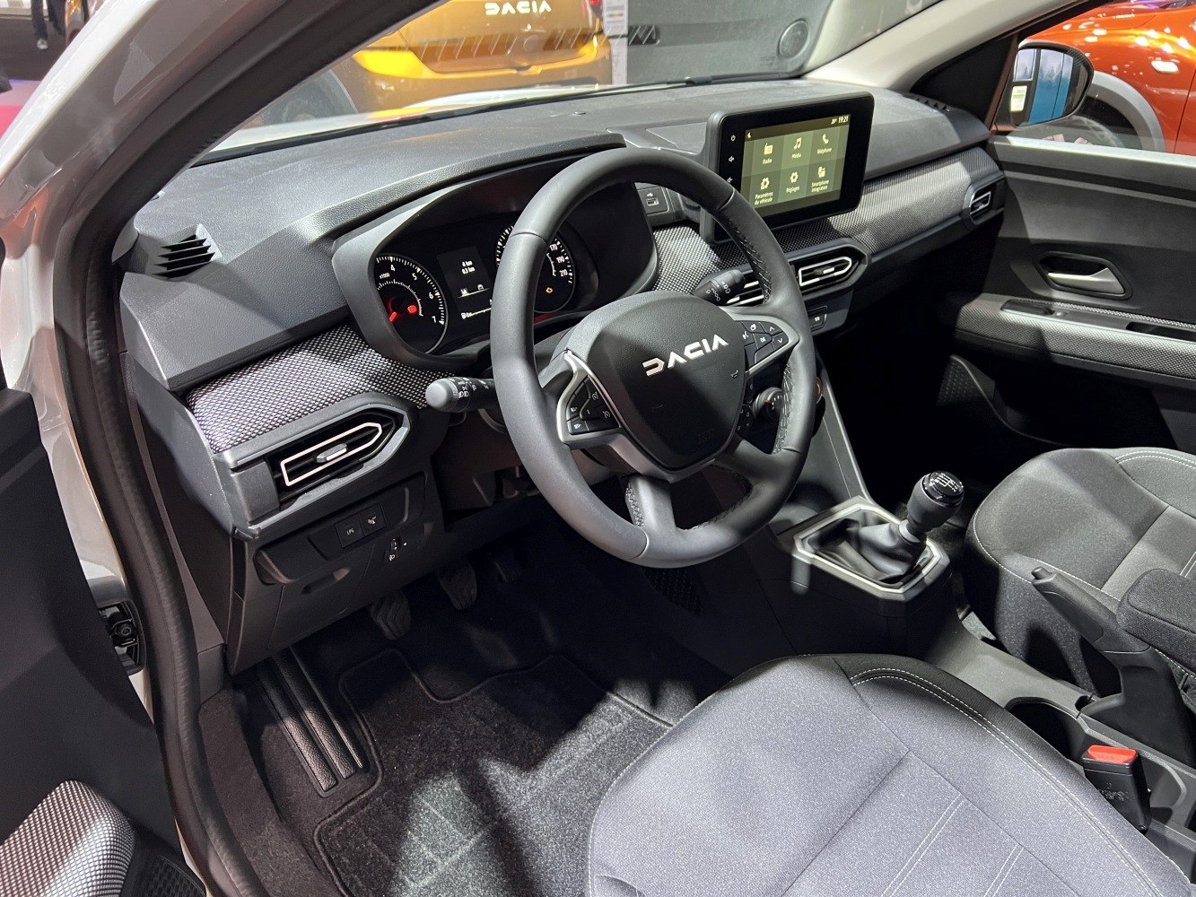 Interior with steering wheel, manual gear stick, and infotainment display