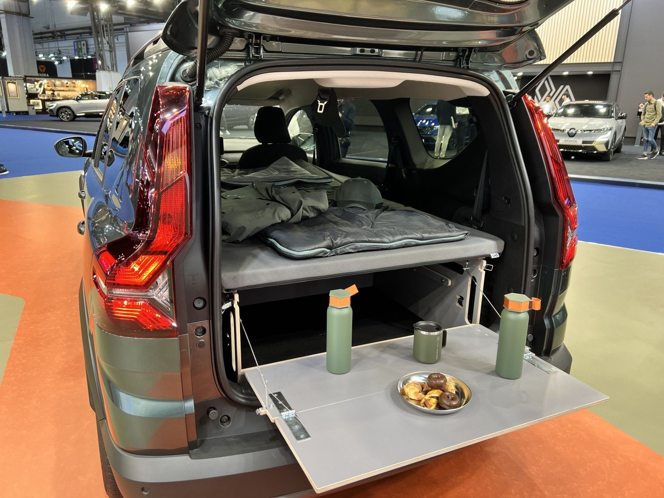 SUV rear with fold-out tailgate table and camping sleeping setup