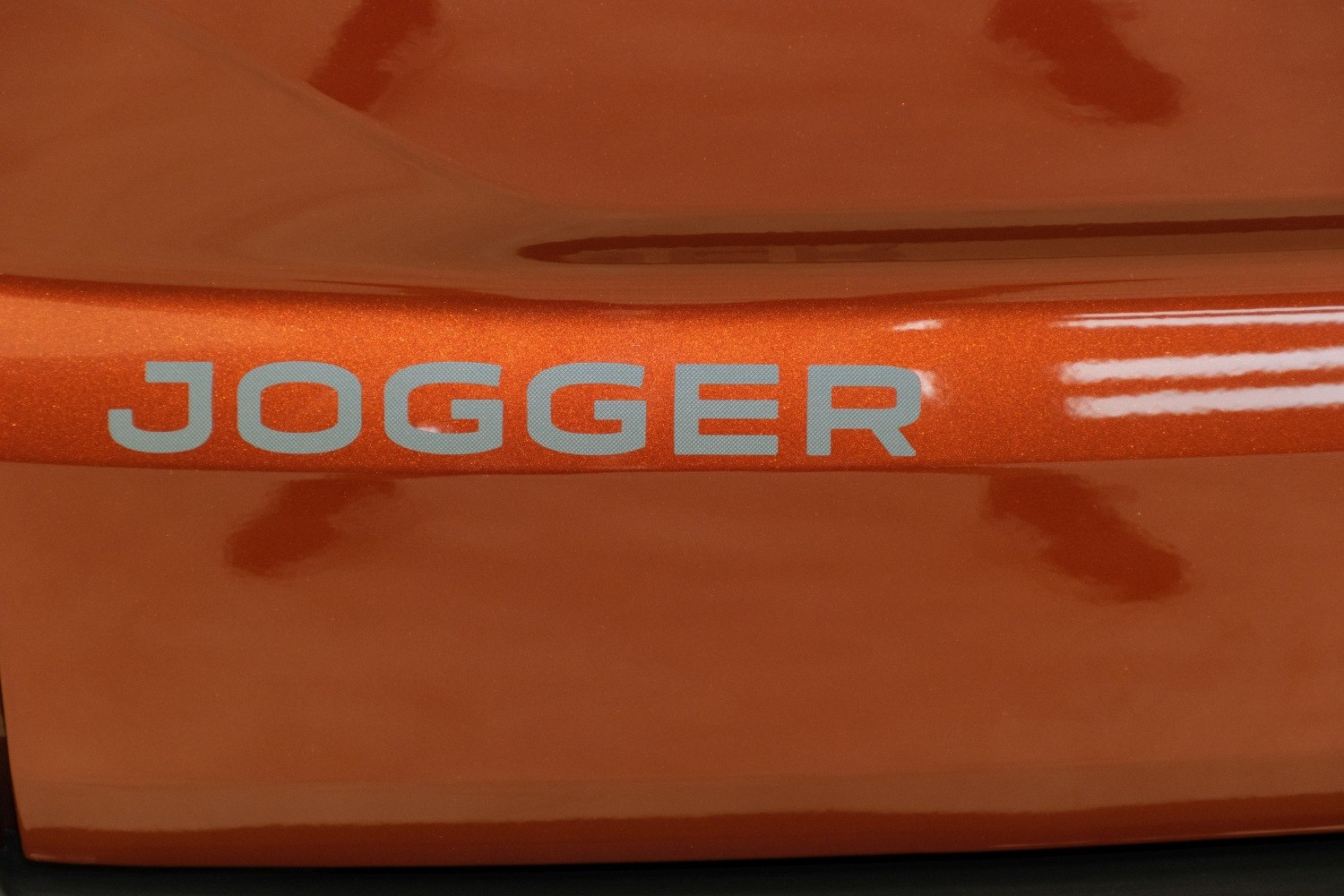 Close-up of metallic car badge lettering on orange body surface