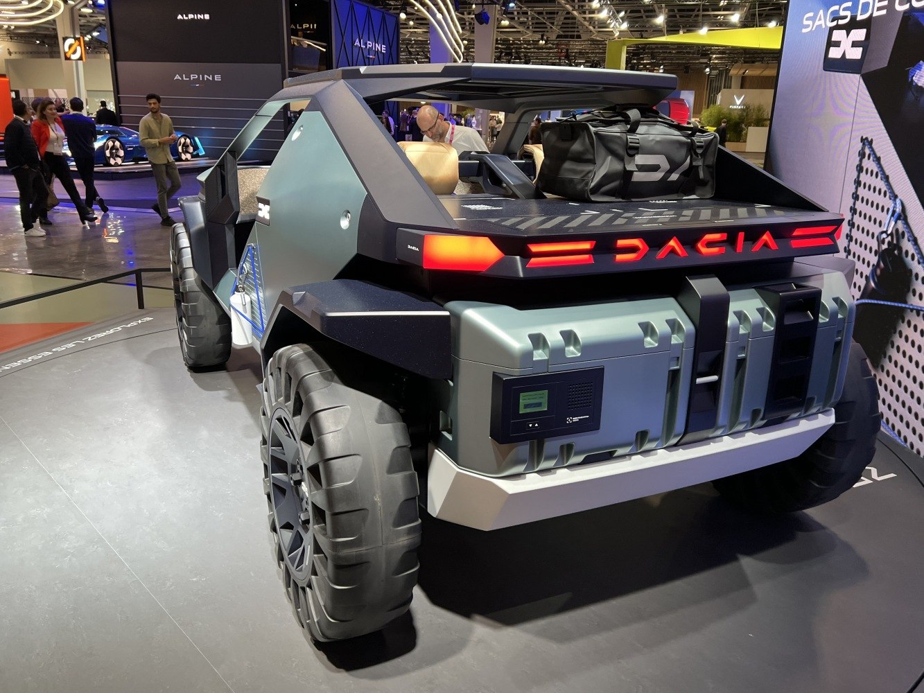 Rear view of a rugged, open-cargo concept vehicle with oversized off-road tires.