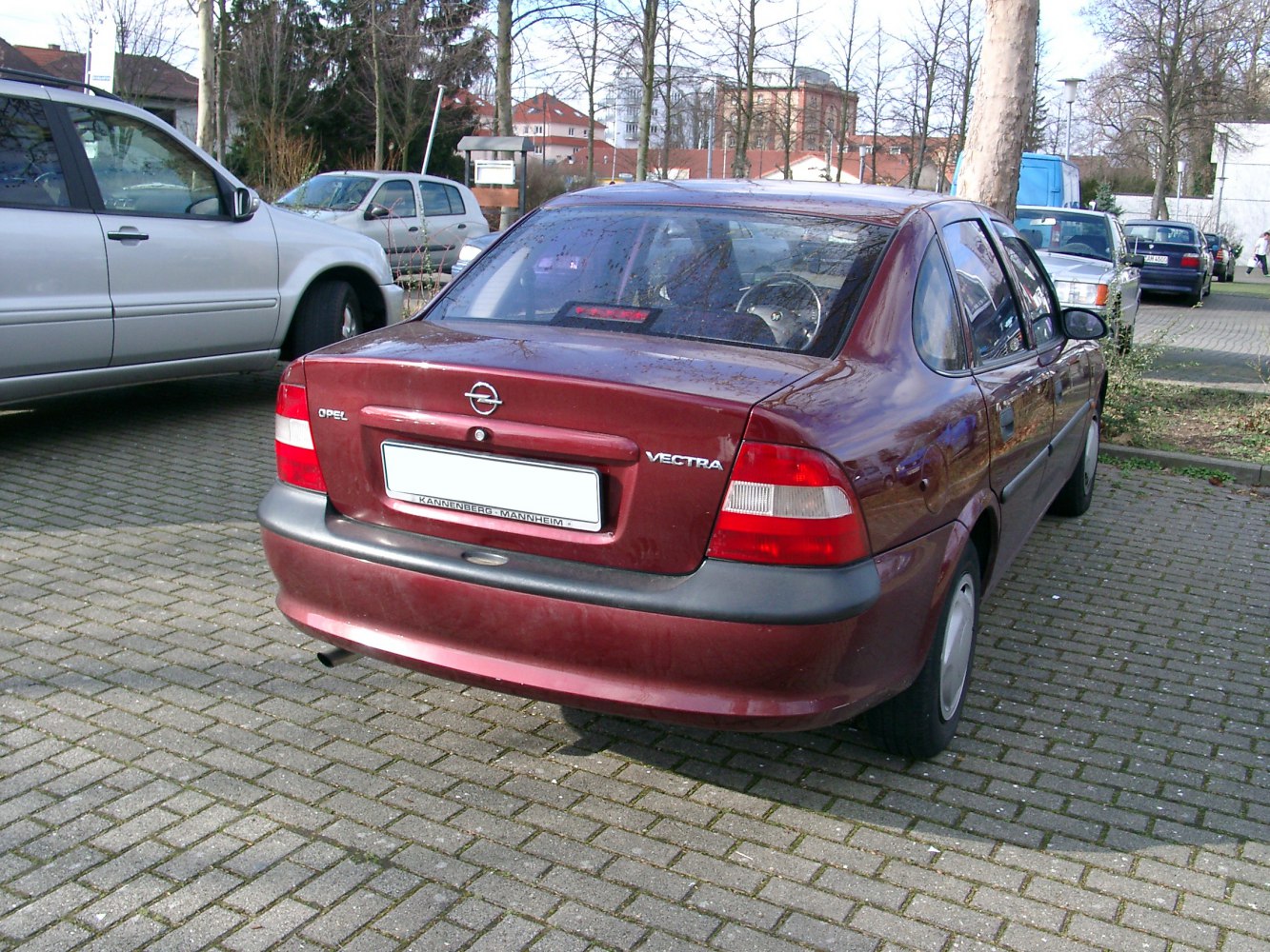 Rear view of a 1990s sedan with prominent tail lights and trunk.