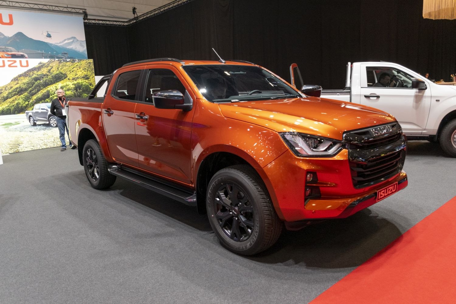 Orange double cab pickup truck with bold front grille and black wheels.