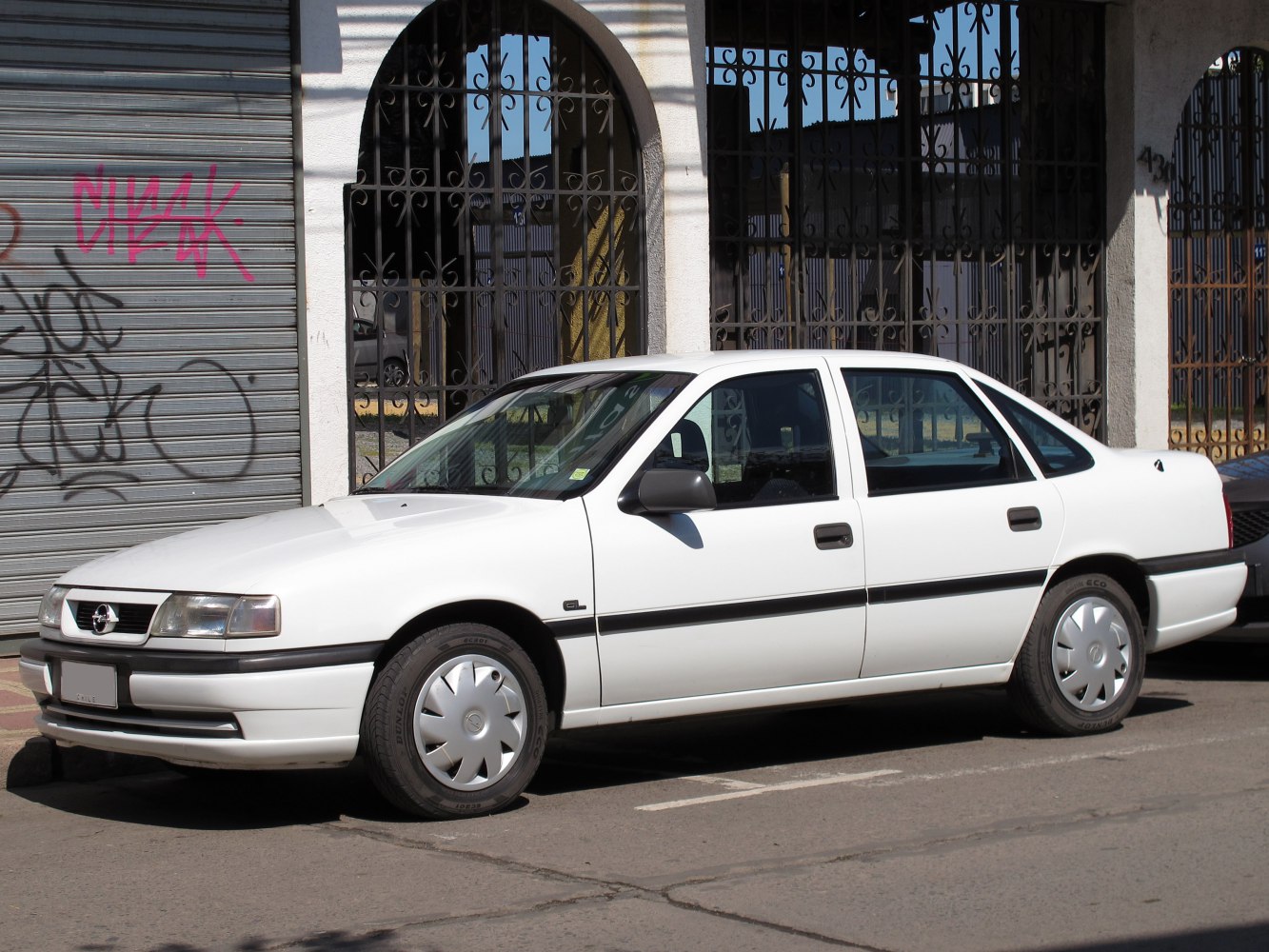 White 1990s four-door sedan with smooth body and hubcaps