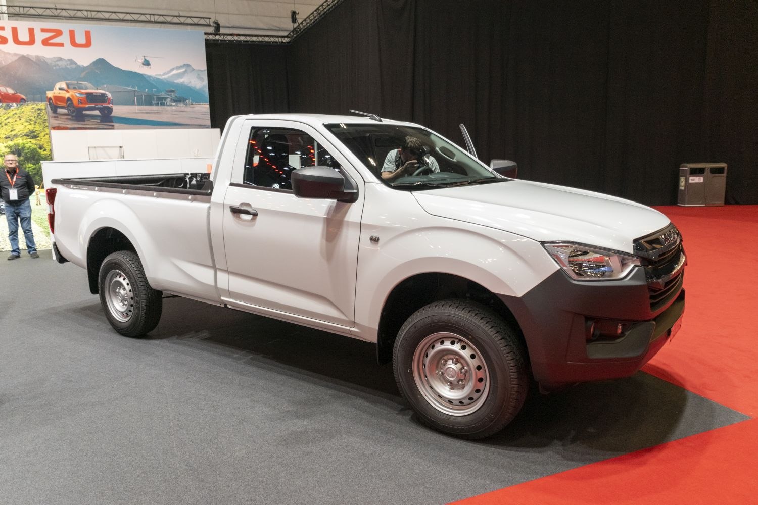 Front side view of a single cab pickup truck with flatbed and steel wheels