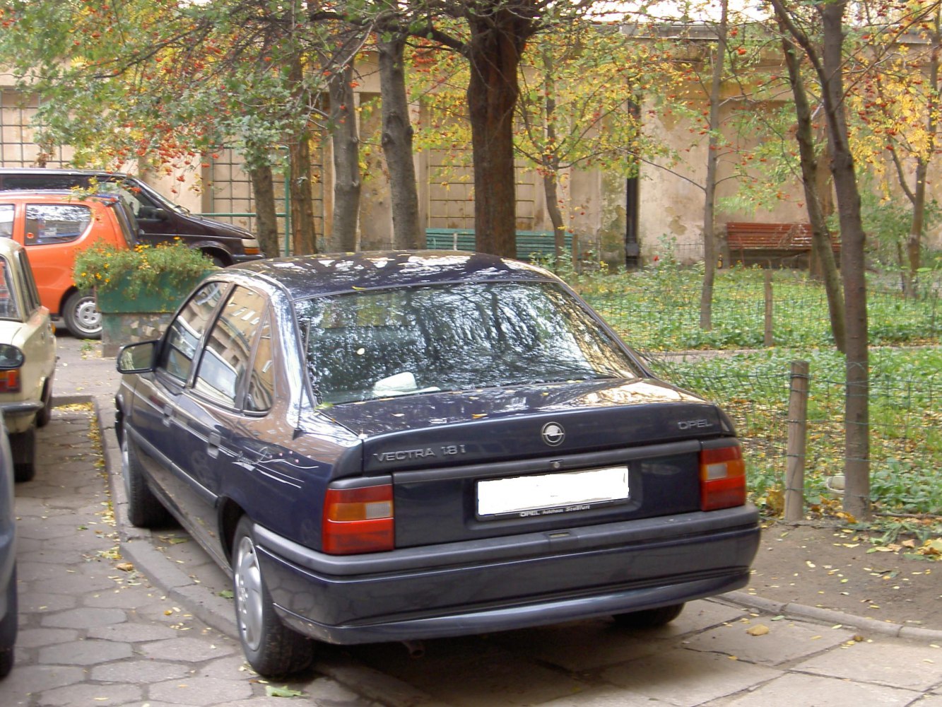 Rear of a 1990s facelift sedan with distinctive tail lights and blue paint.