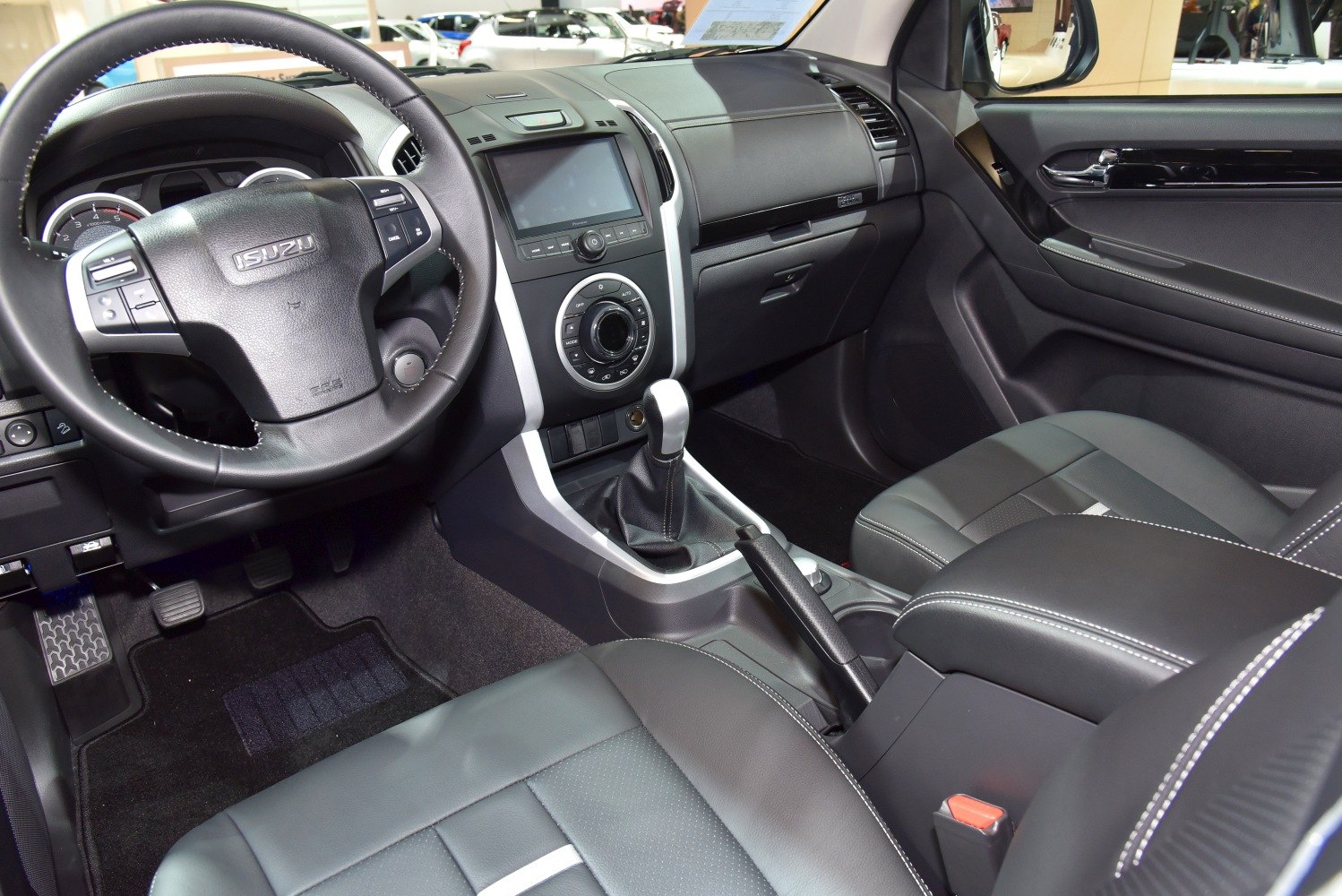 Interior shot of steering wheel, dashboard, gear shift, and seating