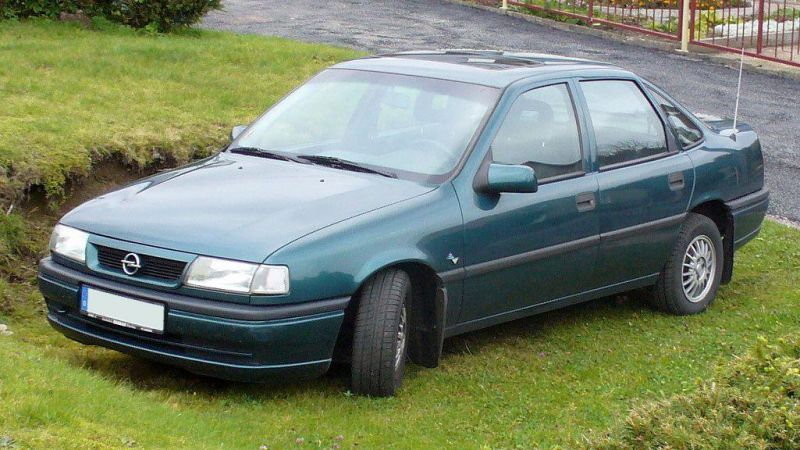 Green sedan with alloy wheels parked on grass, front-side view