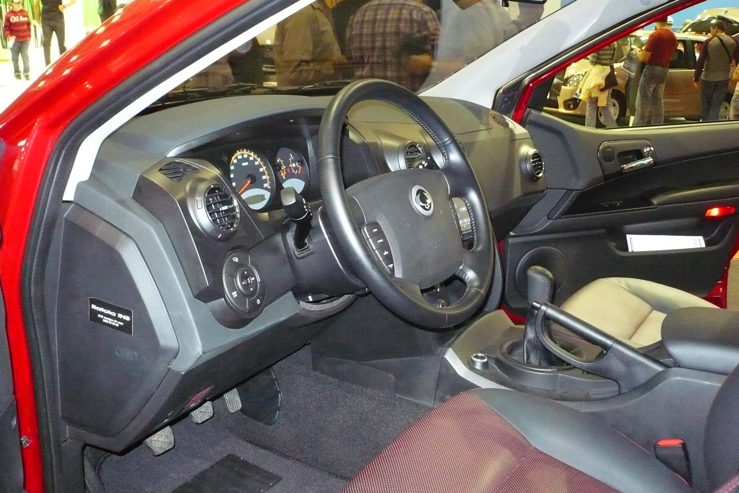 Steering wheel, dashboard, gear lever, and front seating area.