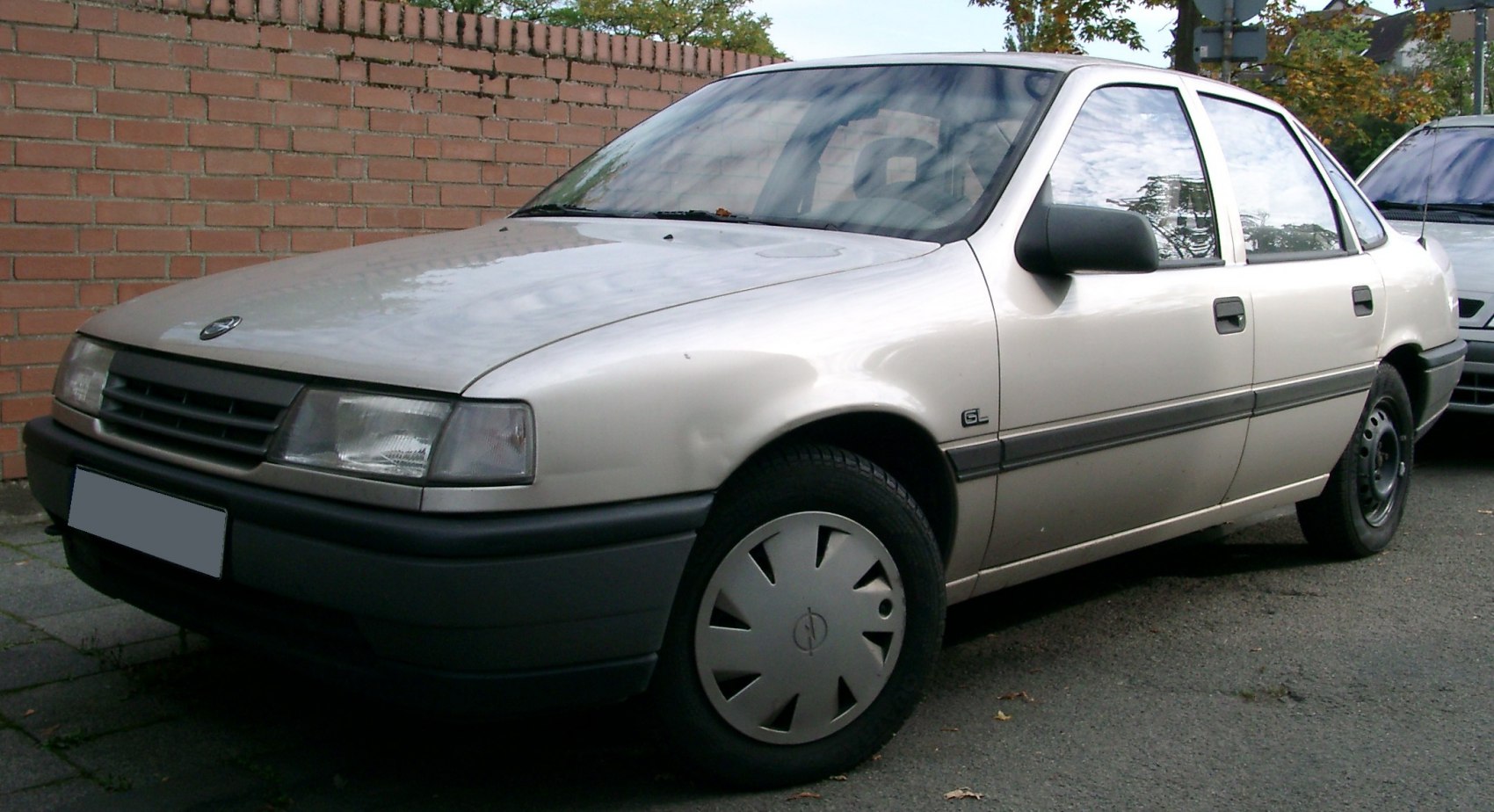 Front-side view of beige sedan with rectangular headlights and hubcaps