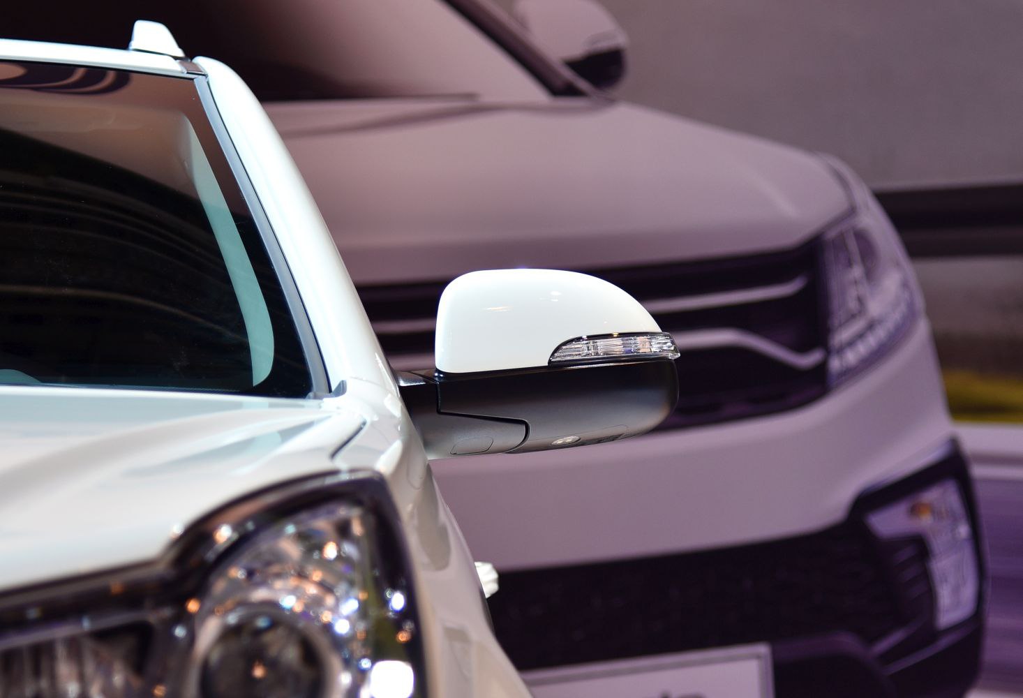Close-up of a white side mirror and front grille with headlight details
