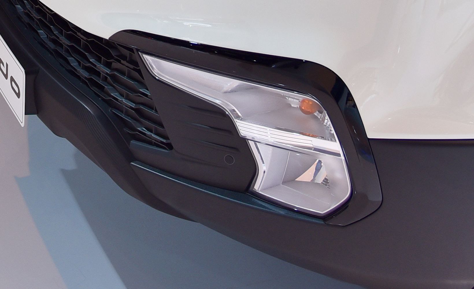 Close-up of front bumper, fog light, and mesh grille design
