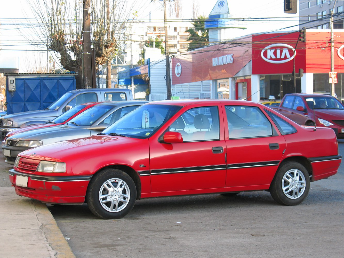 Red four-door sedan with alloy wheels and side profile