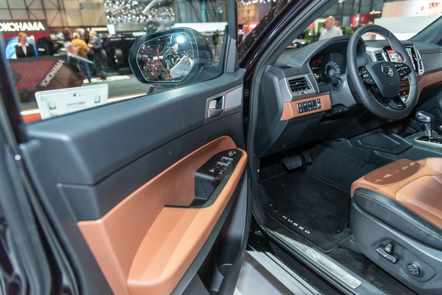 Driver door panel with window controls and brown-black seat interior