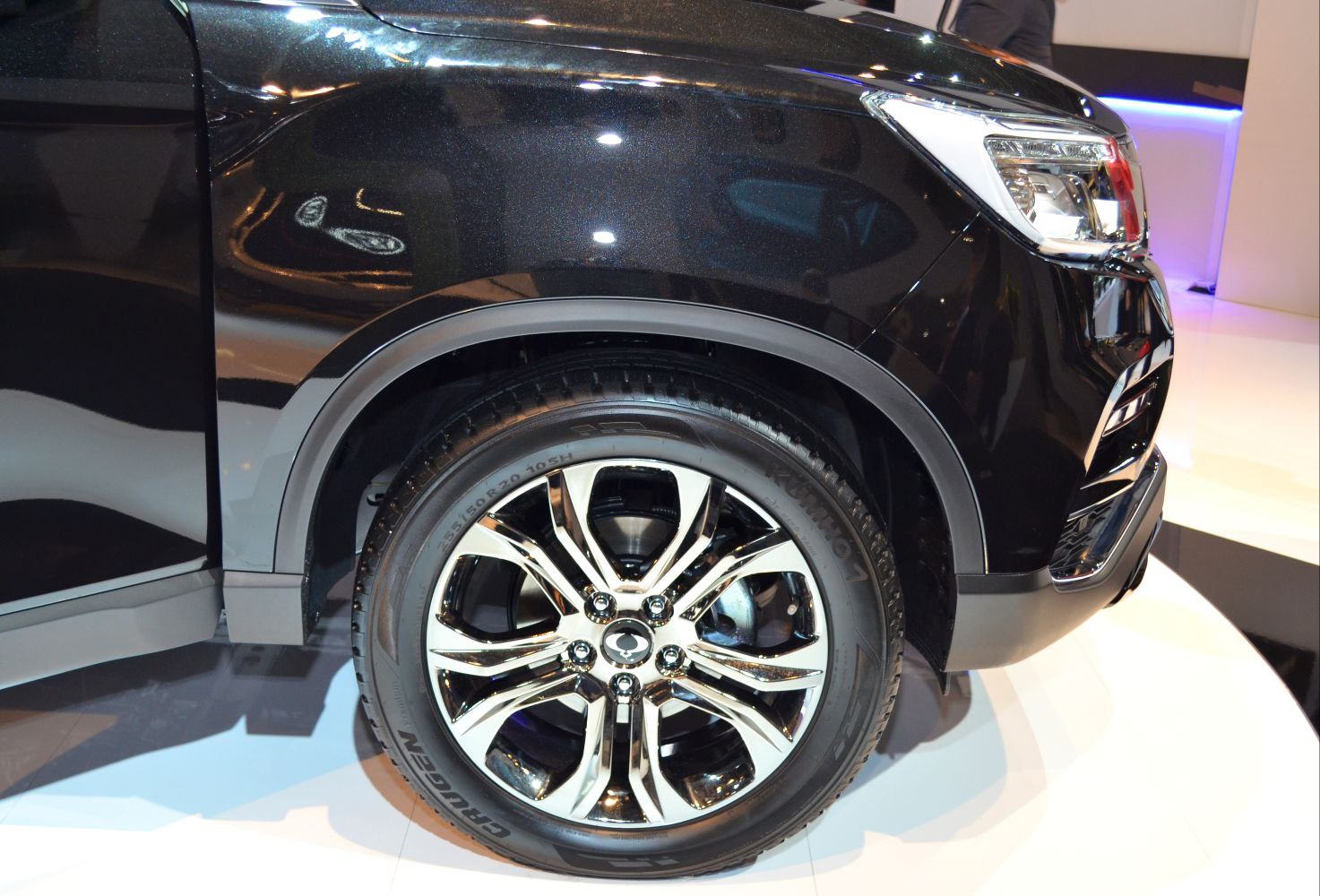 Close-up of alloy front wheel and headlight area with body panel.