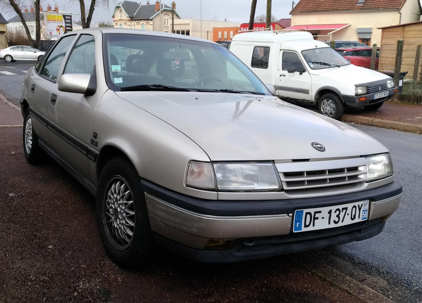 Close-up of sedan front end with rectangular headlights and multi-spoke wheels