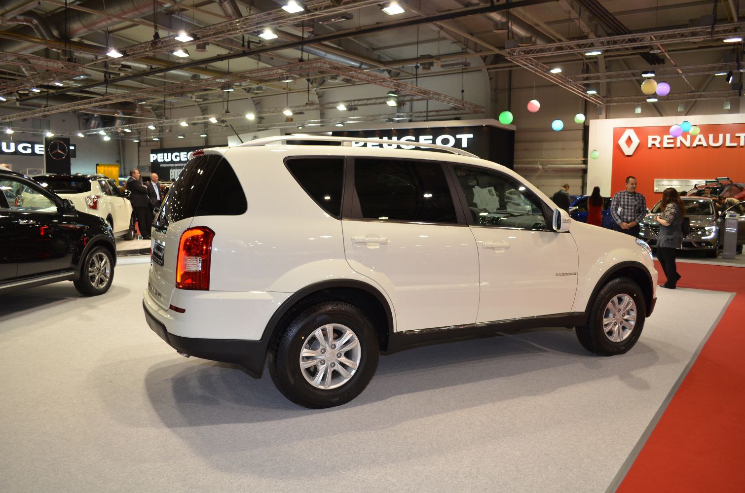 White side and rear view of an SUV with large rear lights and roof rails.