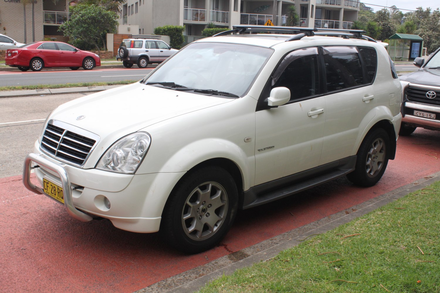 White SUV with front bull bar and roof rack in urban parking