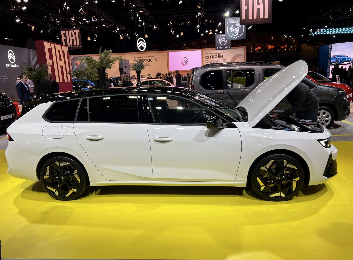 Side view of white station wagon with open hood and sporty black wheels