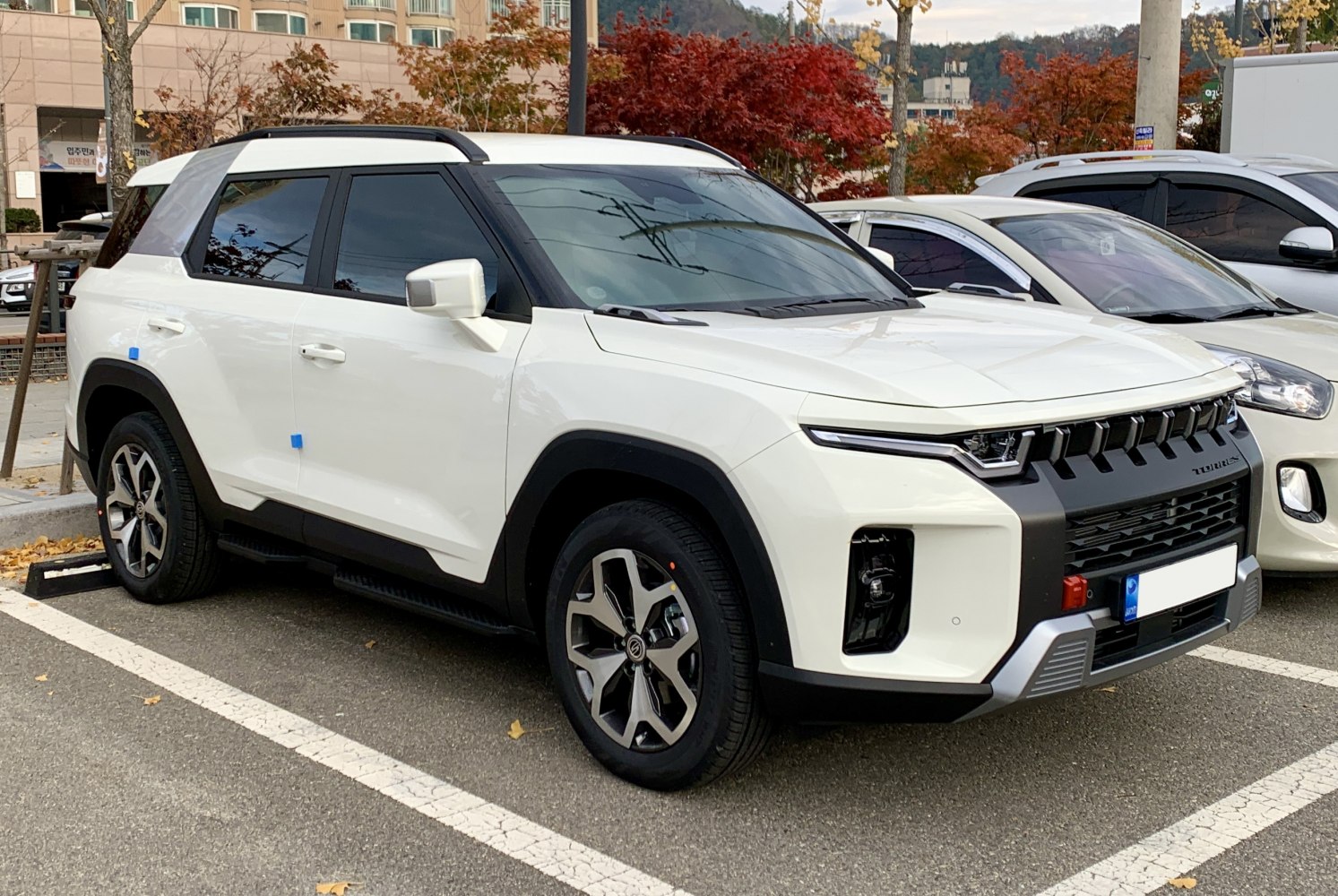 White SUV with bold grille, angular design, and roof rails.