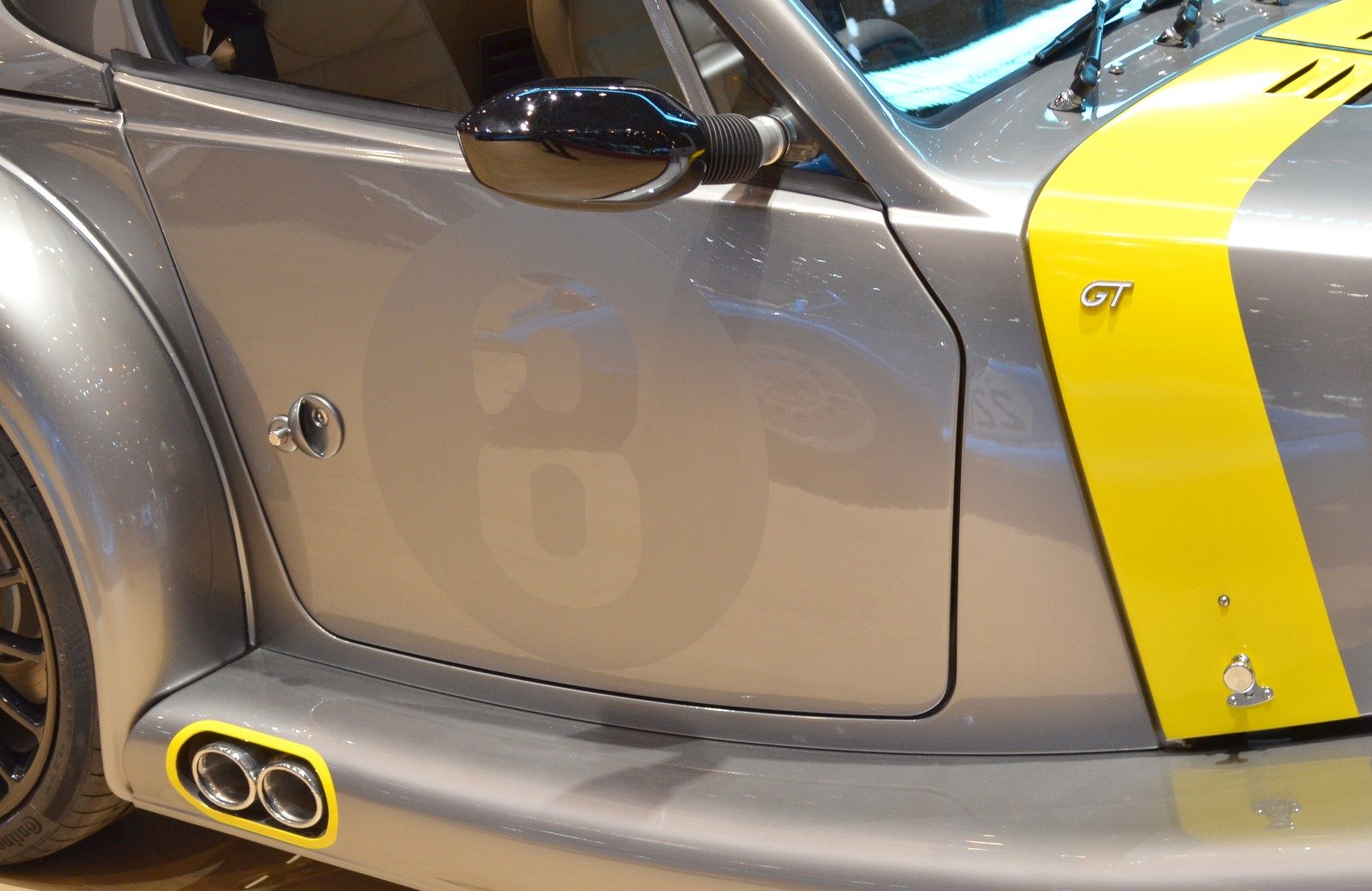 Close-up of side panel with dual exhaust, side mirror, and GT badge