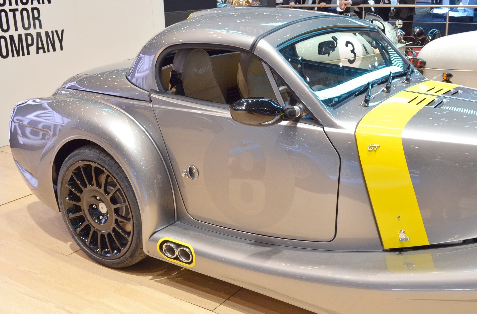 Silver car side with yellow racing stripe, black wheels, and dual side exhaust