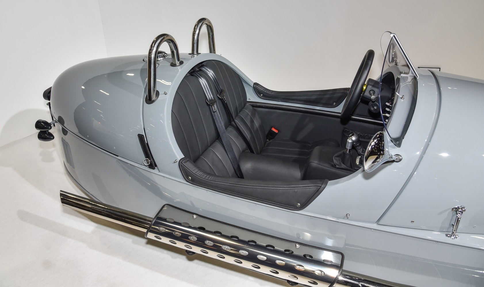 Vintage styled open cockpit with black leather seats and chrome exhaust pipes.