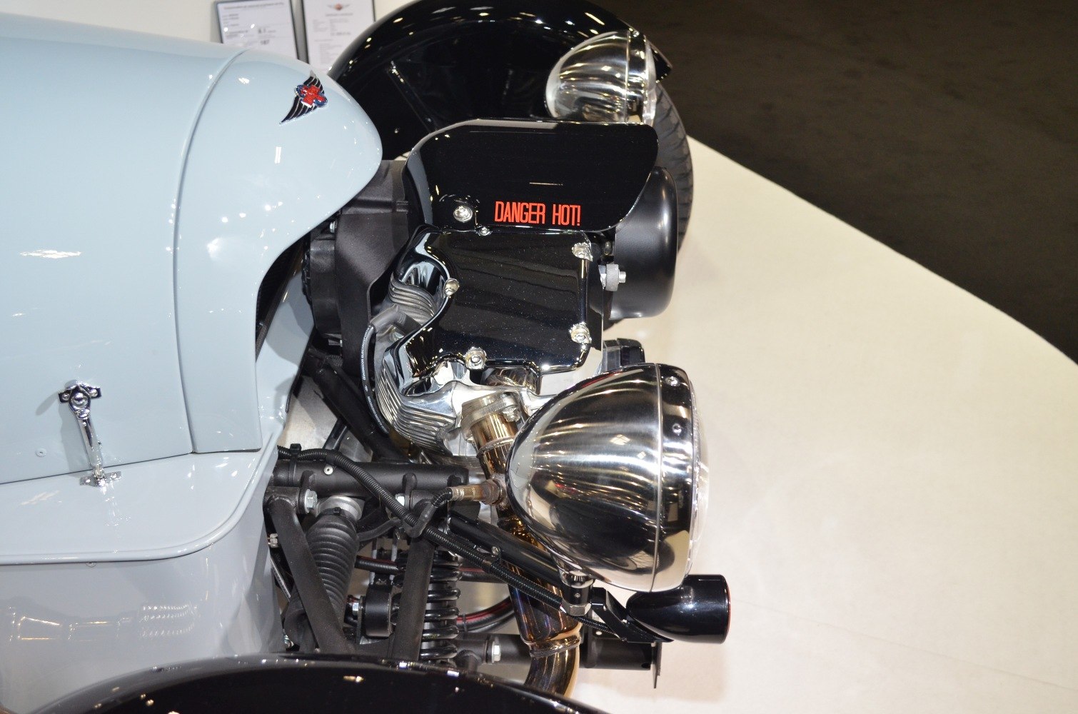 Close-up of engine and front headlight with 'Danger Hot!' warning