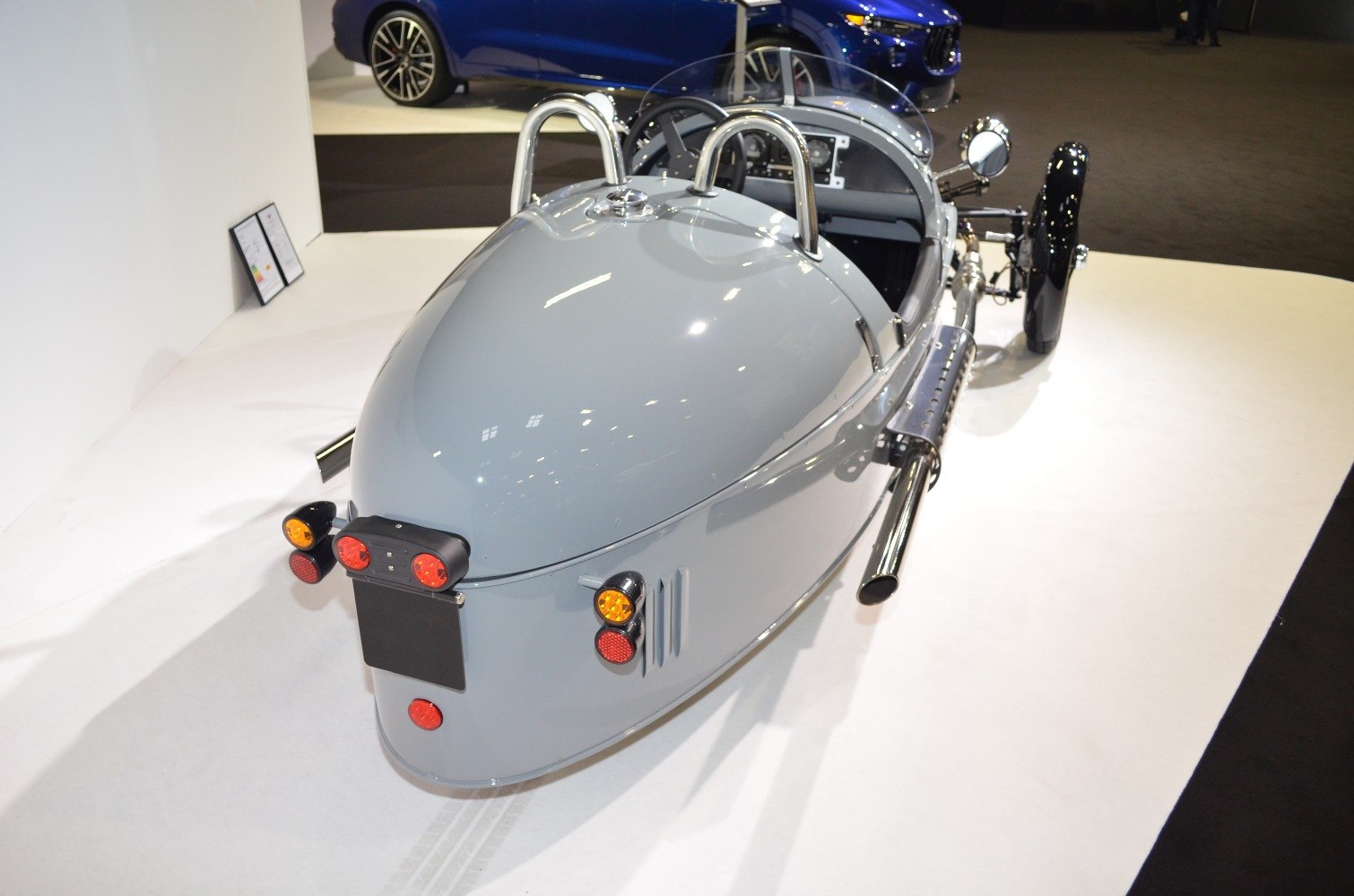 Rear view of three-wheeled retro vehicle with polished side exhaust.