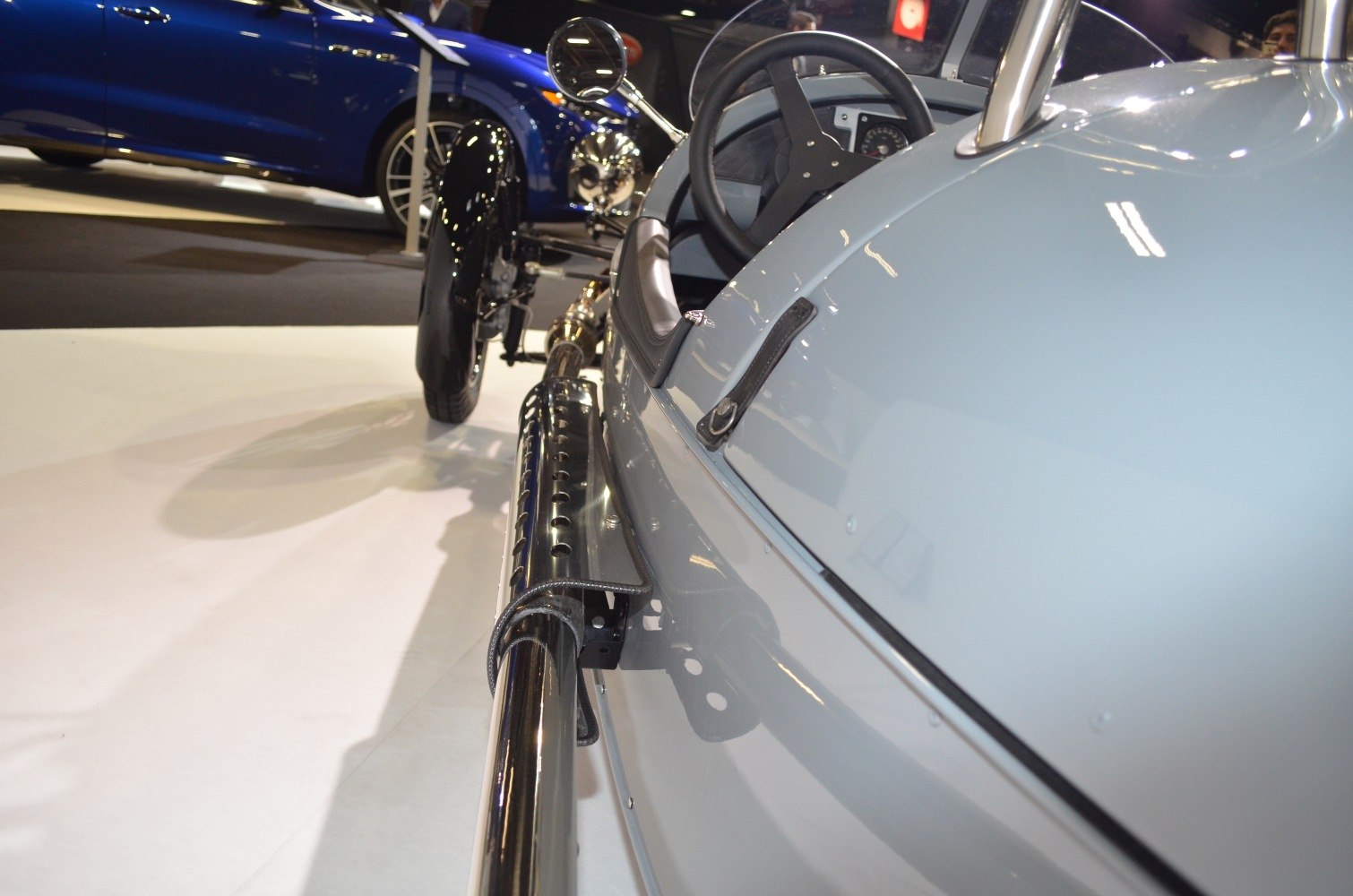 Open cockpit and long side exhaust pipe of a vintage 3-wheeler.