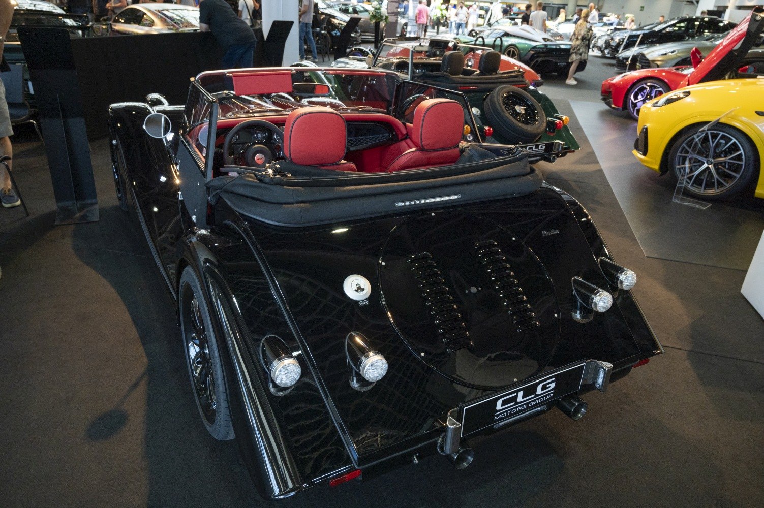 Black convertible roadster with round rear lights and red interior seats