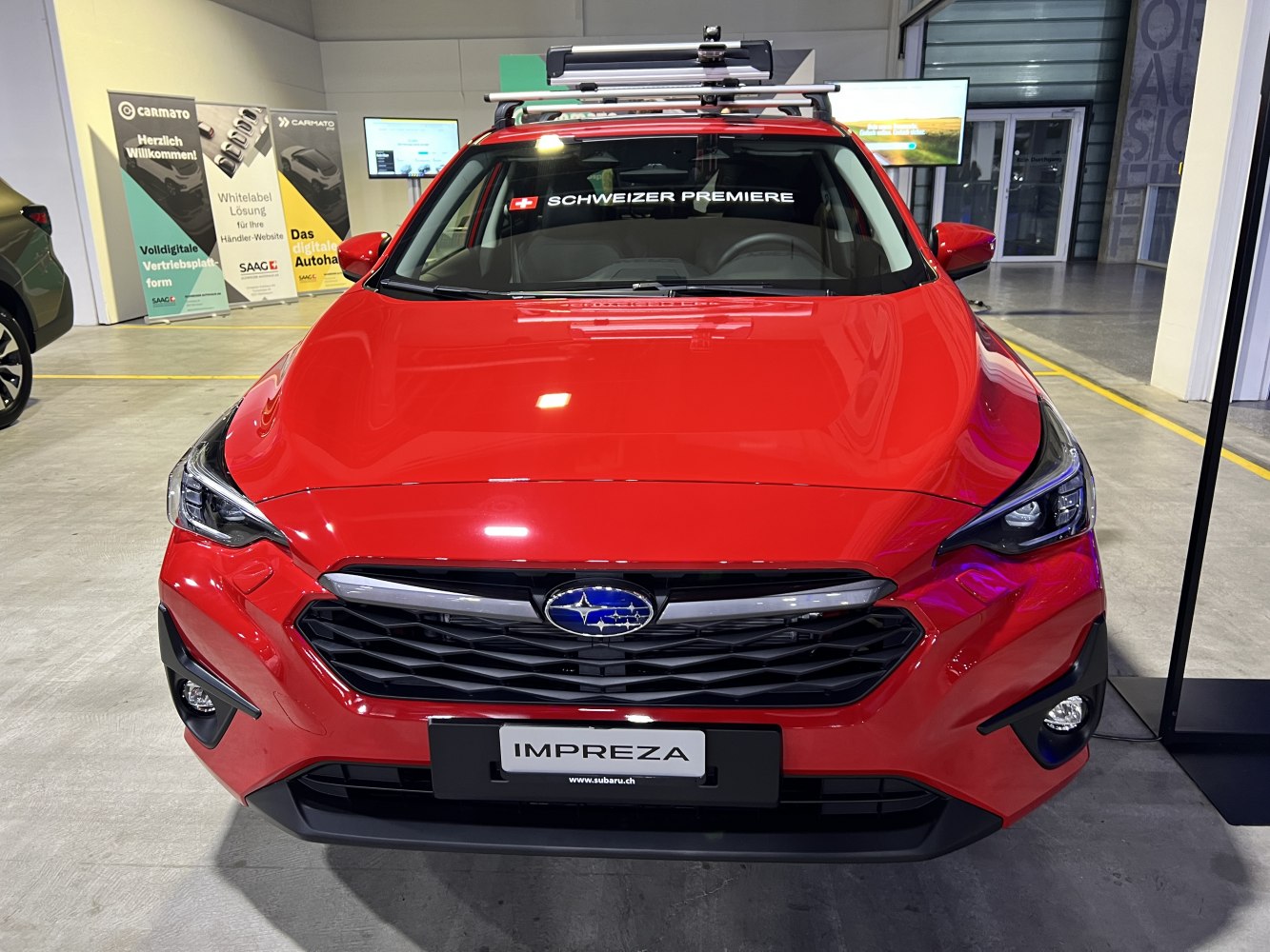 Red hatchback front view with black grille and roof-mounted rack