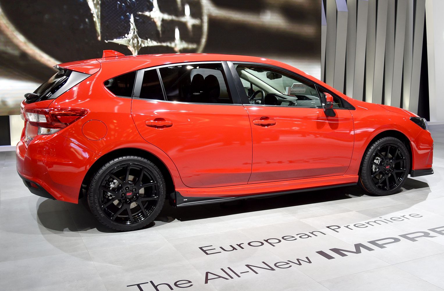 Side profile of red hatchback with black wheels
