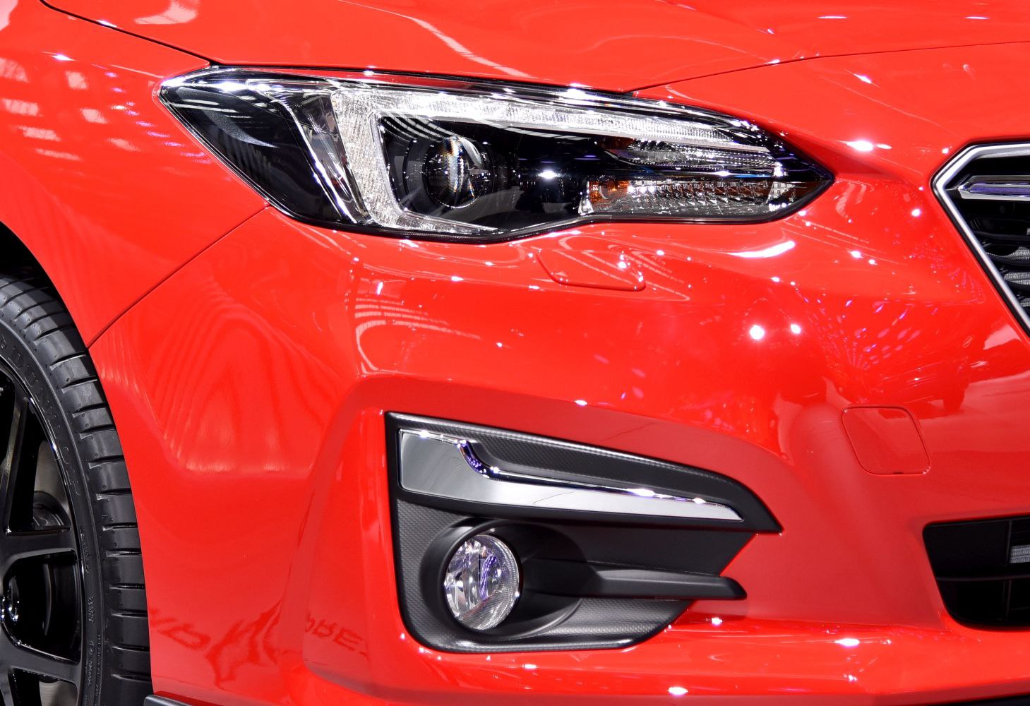 Close-up of headlight and fog light on red front bumper