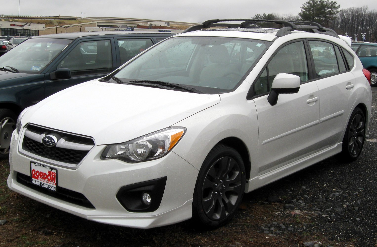 White hatchback with roof rails and alloy wheels in front side view.
