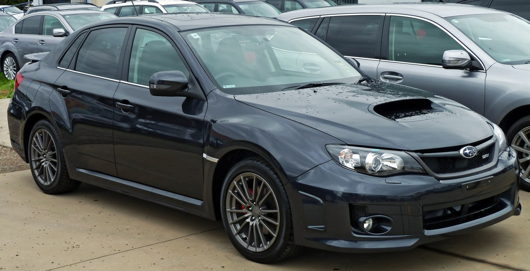 Front side view of sedan with hood scoop and alloy wheels