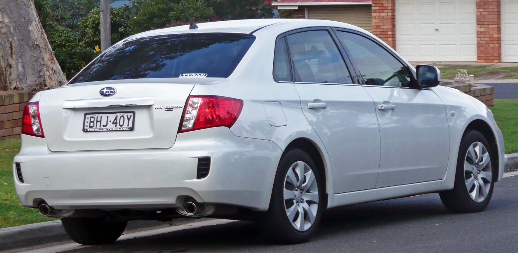 Rear and side view of white sedan with dual exhaust and alloy wheels
