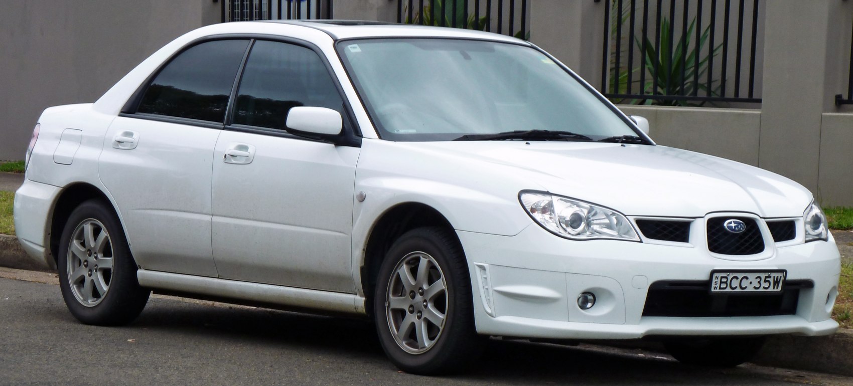 White four-door sedan with facelift front end and alloy wheels.