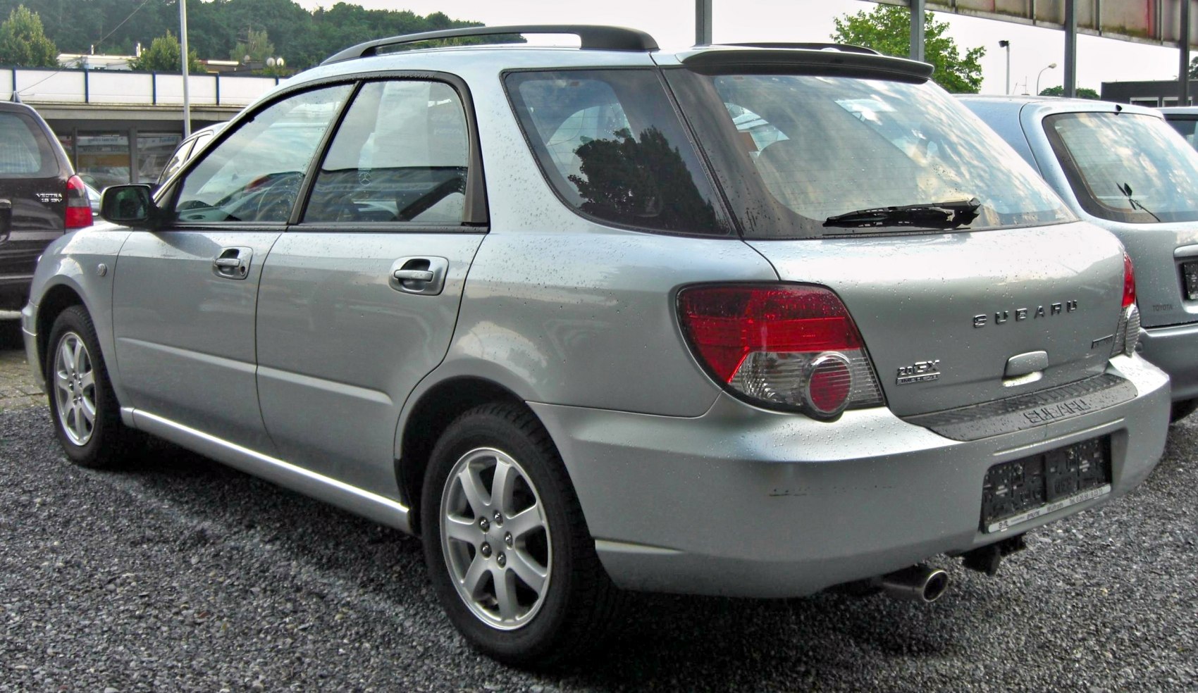 Rear side view of a silver station wagon with alloy wheels and roof rails.
