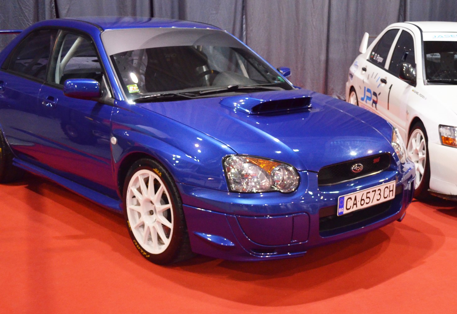Front hood scoop with white multi-spoke alloy wheels on sporty hatchback.
