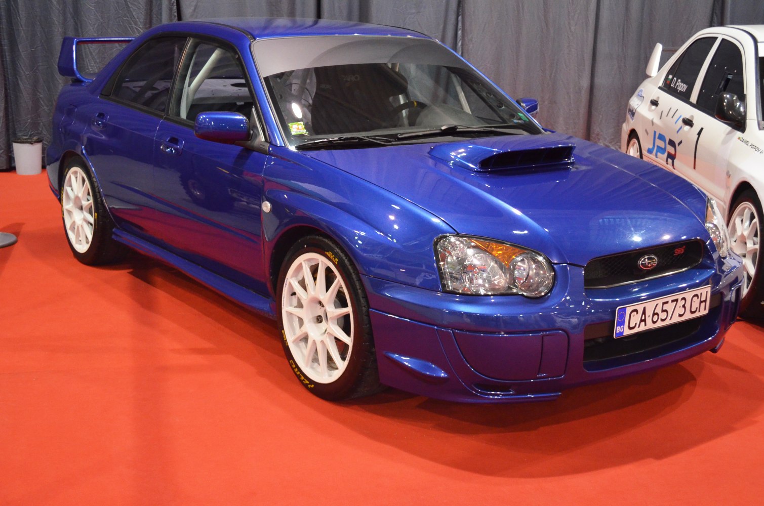 Blue sporty sedan with white wheels and rear spoiler