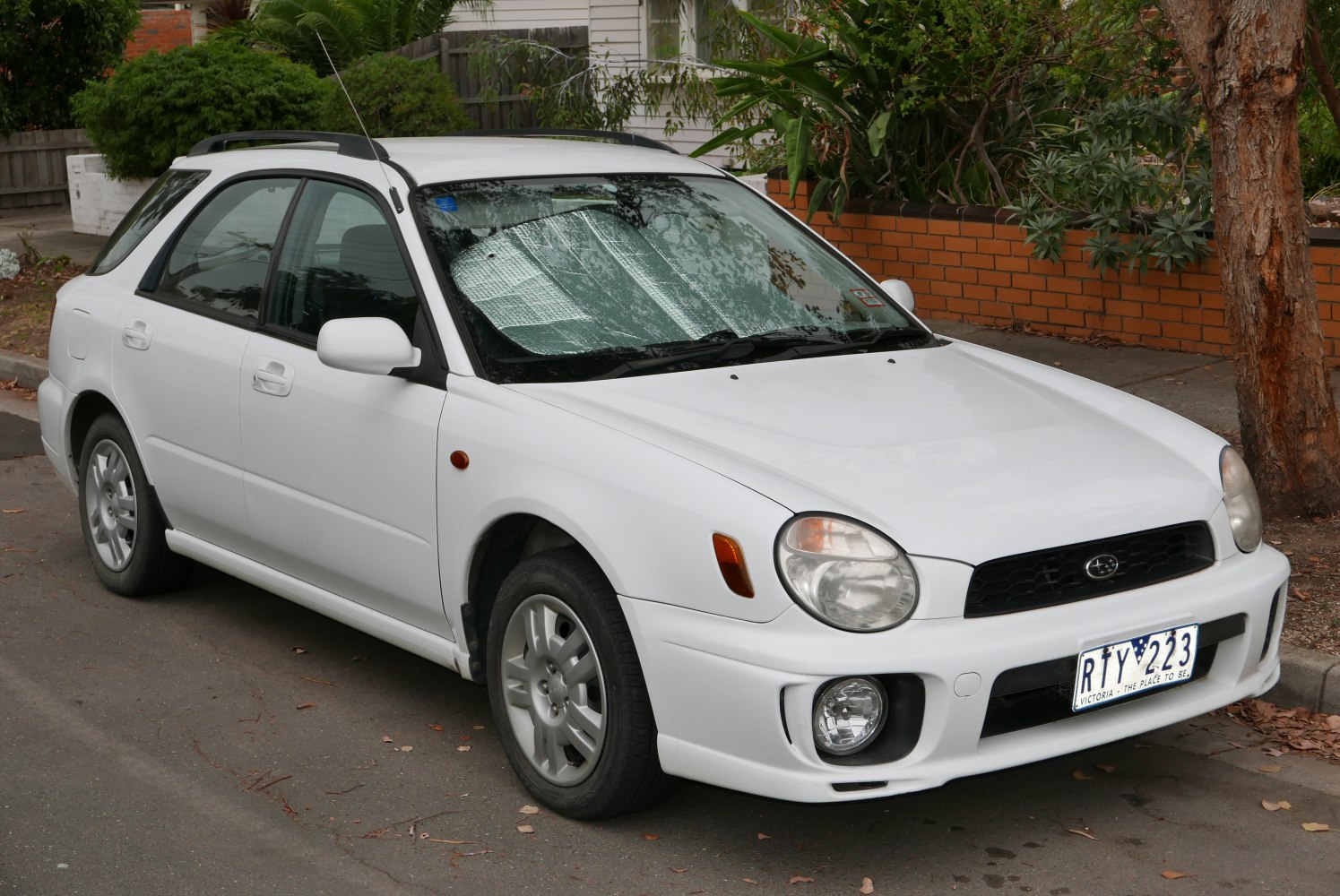 White station wagon with round headlights and roof rails parked on street