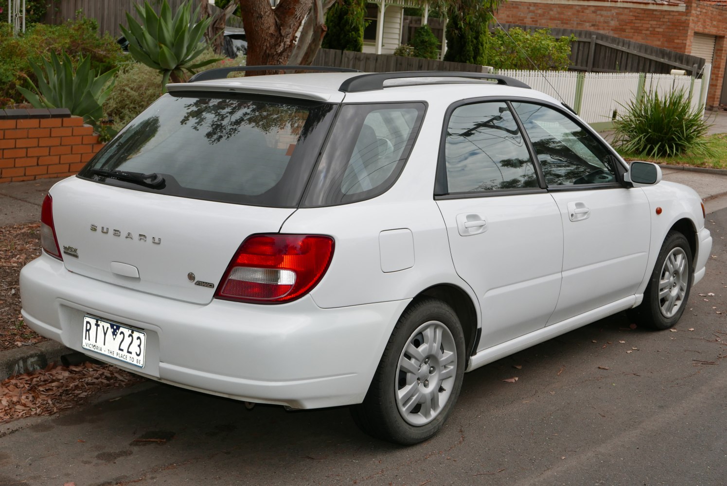 Rear and side view of white station wagon with roof rails and alloy wheels
