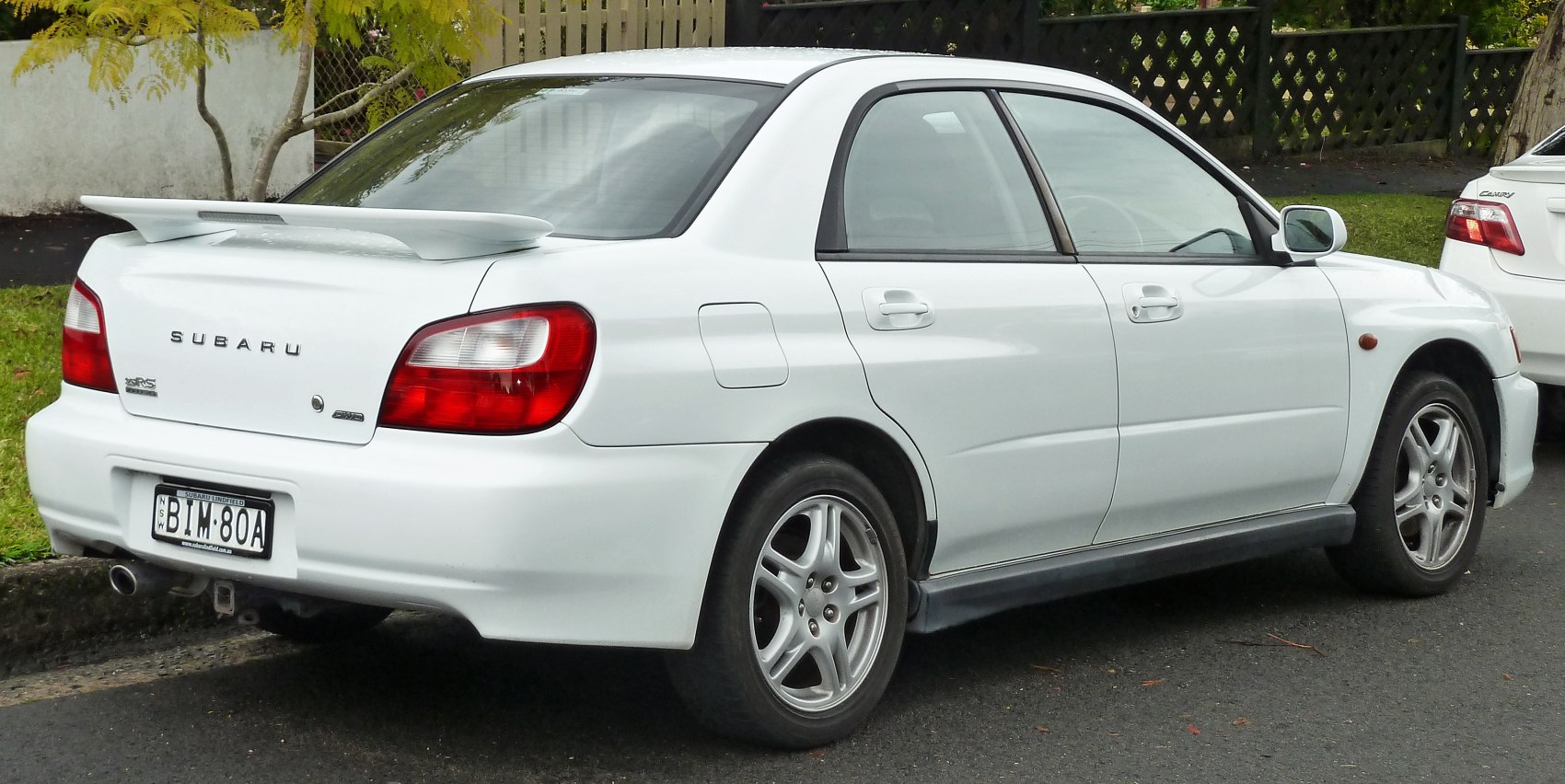 White sedan with rear spoiler and alloy wheels