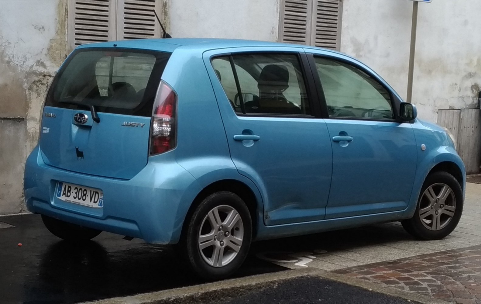 Rear three-quarter view of blue compact hatchback with alloy wheels