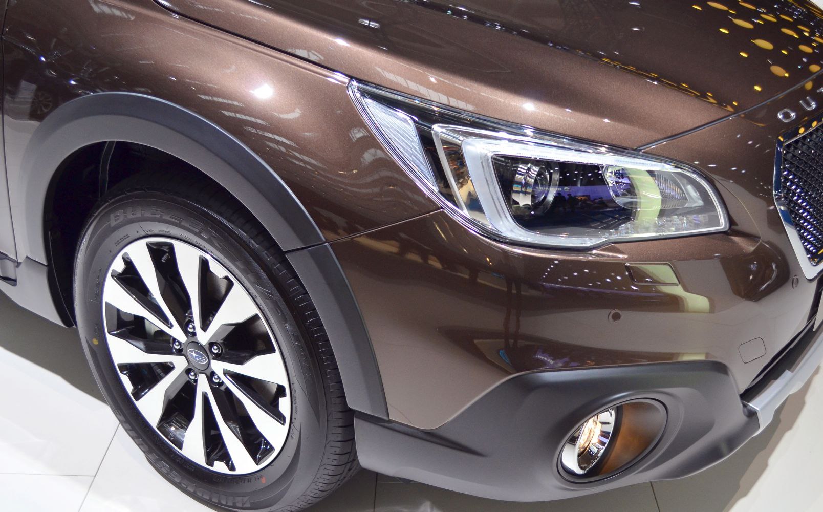 Close-up of front headlight and alloy wheel with rugged body cladding