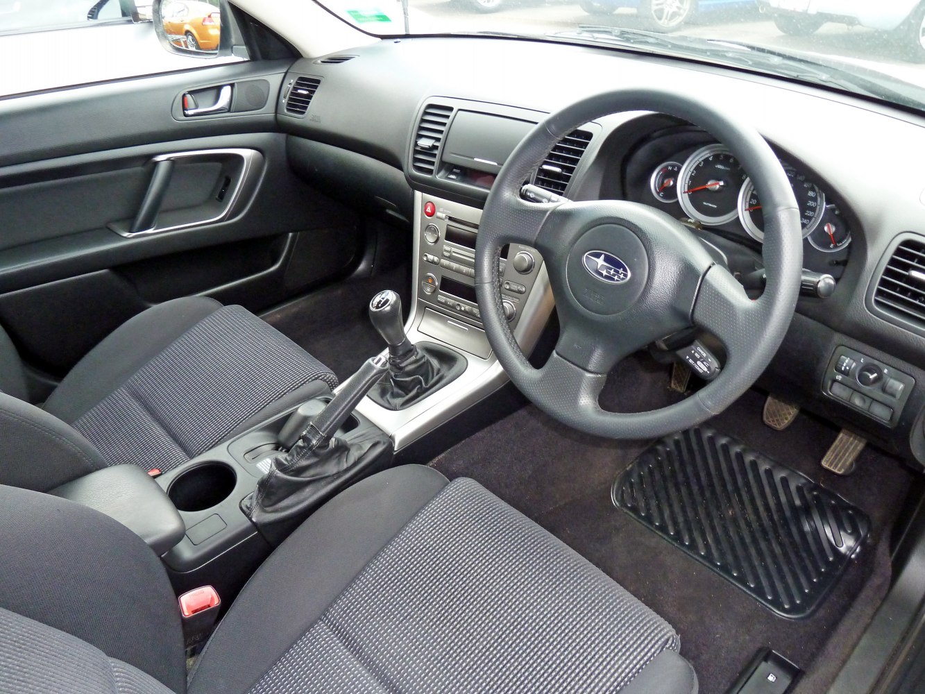 Manual gear stick and three-spoke steering wheel with dashboard controls